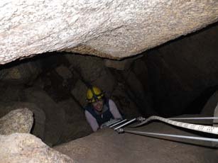 A caver uses a wire caving ladder in the Armageddon Cave at Mt. Buffalo. Note the rungs are up against the rock, which makes getting your hands and feet in difficult.